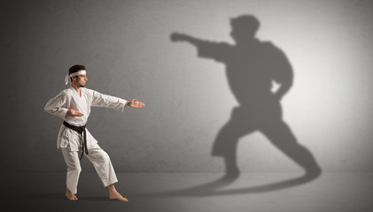 Fototapeta na wymiar Young karate man confronting with his own shadow 