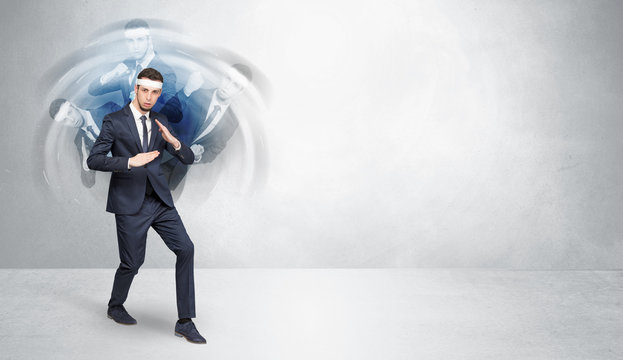 Young businessman in suit fighting with empty wall background
