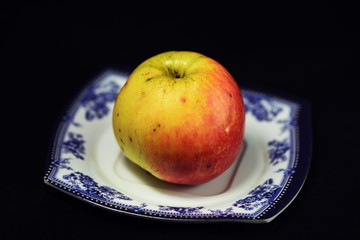 small apple on a plate with black background