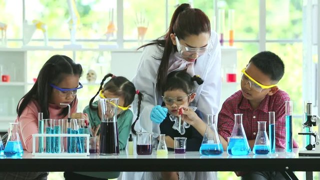 Slow motion scene video of science teacher teach Asian students in laboratory room, Student drop something into beaker, concept for study in laboratory room.