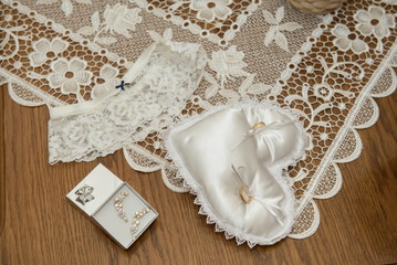 bridal accessories, garter, wedding rings on a white pillow