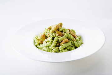 Delicious chicken with green sauce pasta over white background