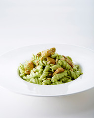 Delicious chicken with green sauce pasta over white background