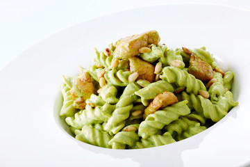 Delicious chicken with green sauce pasta over white background