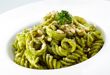 Delicious pine nuts with green sauce pasta over white background