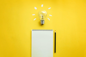 Flat lay of light bulb and empty memo pad and pencil on yellow background with texts. Conceptual brain storming still life. - obrazy, fototapety, plakaty