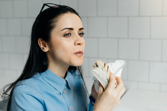 Beautiful Brunette Female Student In Blue Shirt Eating A Sandwich Before Class At The University