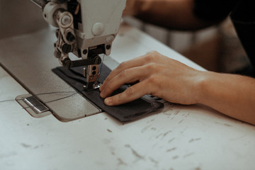 Close up of sewing machine working part with leather. The master's hands sews a leather product. Handmade concept.