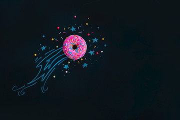 Space donut with a chalk drawing of a shooting star, comet tail and stars. Flat lay food...