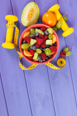 Fresh fruit salad and centimeter with dumbbells, healthy lifestyle and nutrition concept