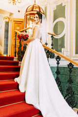 The bride in an expensive luxury hotel with a bouquet. Standing on the stairs and in the hallway.