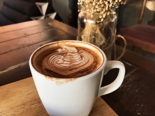 A cup of mocha which coffee art on wooden table in café. There is mouth print at beside edge of cup.