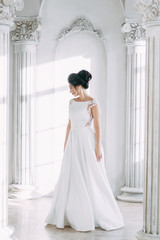 Beautiful girl in a wedding dress with a bouquet. Bride in a bright Sunny Studio.