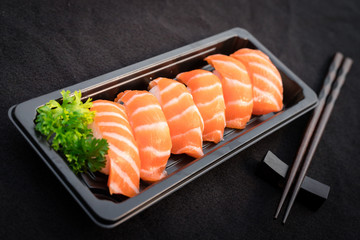 sashimi sliced peice serve in black plastic plate with chopstick on black tablecloth