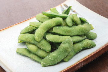 close up of Green peas in shell Sprinkle salt serve with japanese plate style on wooden table