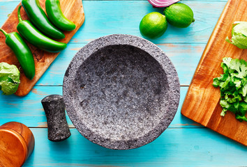 empty molcajete on table with ingredients ready to prep