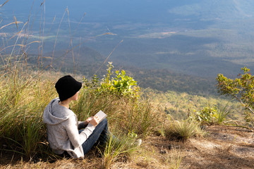 Woman sitting reading and writing looking out at beautiful natural view