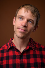 Man wearing red checkered shirt against brown background