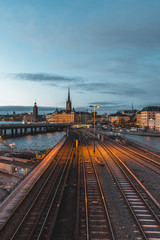 Fototapeta na wymiar Evening cityscape with subway train crossing the bridge of Gamla Stan, Stockholm, Sweden. City hall and cathedral in background