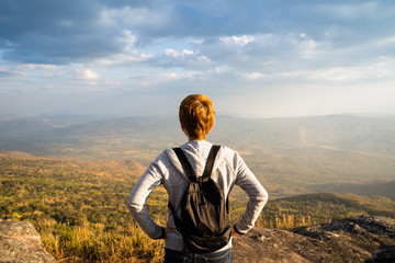 Naklejka premium A woman standing on rocky mountain looking out at scenic natural view and beautiful blue sky