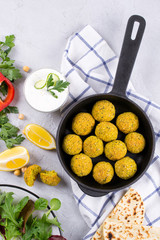 Traditional middle eastern homemade dishes falafel, pita, served with vegetables and spices on concrete background table. Top view