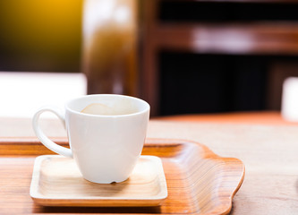 Hot coffee in a white cup on a wooden table.