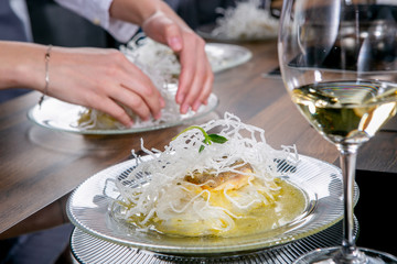 Chef decorates the halibut with mango sauce and rice noodles. Master class in the kitchen. The process of cooking. Step by step. Tutorial. Close-up