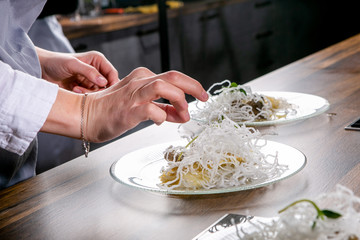 Chef decorates the halibut with mango sauce and rice noodles. Master class in the kitchen. The process of cooking. Step by step. Tutorial. Close-up