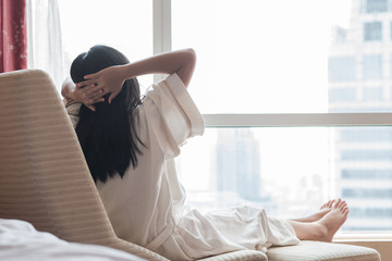 Easy lifestyle Asian woman waking up in the morning taking some rest relaxing in cozy hotel room