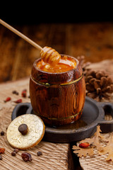 A barrel with fresh fragrant honey and a wooden spoon on a texture saw with cedar cones.
