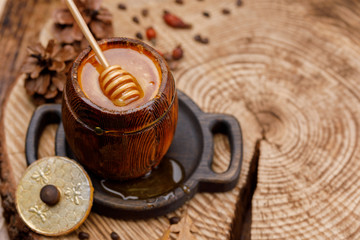 Barrel with fresh delicious honey and honey stick drowning in it. Copy space.