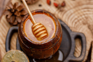 Honey stick immersed in a barrel with fresh honey appetizing.