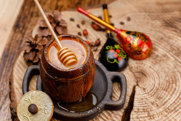 Honey stick dipped in a barrel with fresh appetizing honey and painted Russian wooden spoons. Rustic.