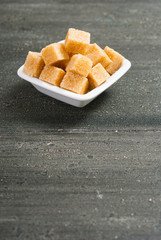 brown sugar cubes on white square dish, dark wood table
