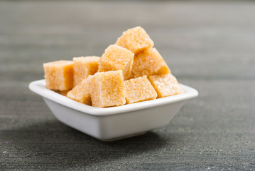 brown sugar cubes on white square dish, dark wood table