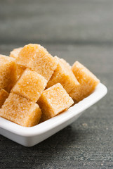 brown sugar cubes on white square dish, dark wood table