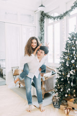 Young couple near the Christmas tree with gifts. Photo shoot in a bright interior Studio for the New year.