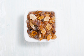 rock sugar in square dish, on white  wooden surface