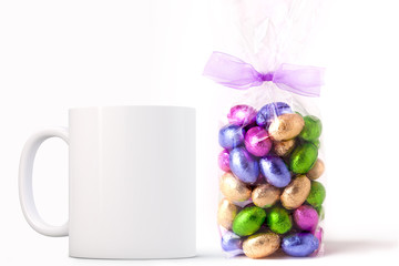 White Mug Mockup - Easter theme. Bag of Easter mini chocolate eggs next to a blank white mug. Perfect for businesses selling mugs, just overlay your quote or design on to the image..