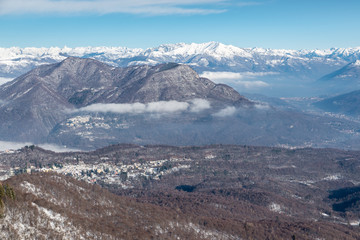 Fototapeta premium Italy. Campo dei Fiori Regional Park in the foreground, with Castello Cabiaglio village, in the background the Alpine chain. The town of Luino on lake Maggiore and Valcuvia are also visible