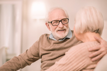 Cheerful pensioner looking into eyes of his wife