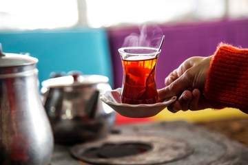 Girl holding a cup of tea near the stove . Winter concept .