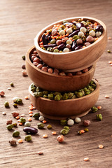 Mixed raw dried Indian legumes in wooden bowls on rustic background with copyspace.