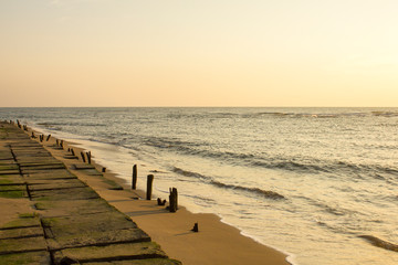 concrete embankment on the background of a sandy beach and the sea under a gray evening sky