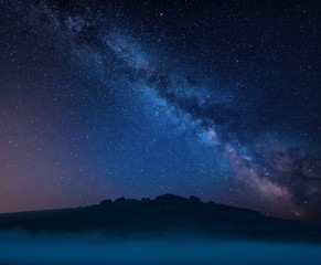 Fototapeta na wymiar Stunning vibrant Milky Way composite landscape image over the tors in Dartmoor revealing peaks through the mist