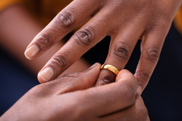 Man Putting An Engagement Ring On Woman's Finger