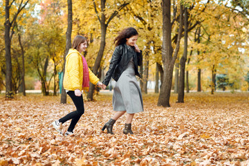 Two happy girls running in autumn city park.