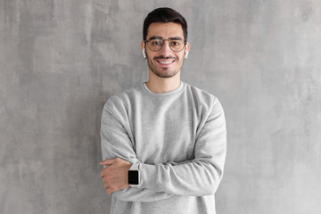 Young handsome man standing with crossed arms against gray textured wall