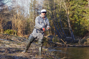 Fisherman with rod on the river bank.