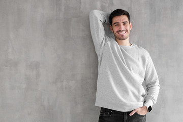 Young man standing isolated against gray textured wall feeling confident and looking optimistic in casual clothes, copy space for your text
